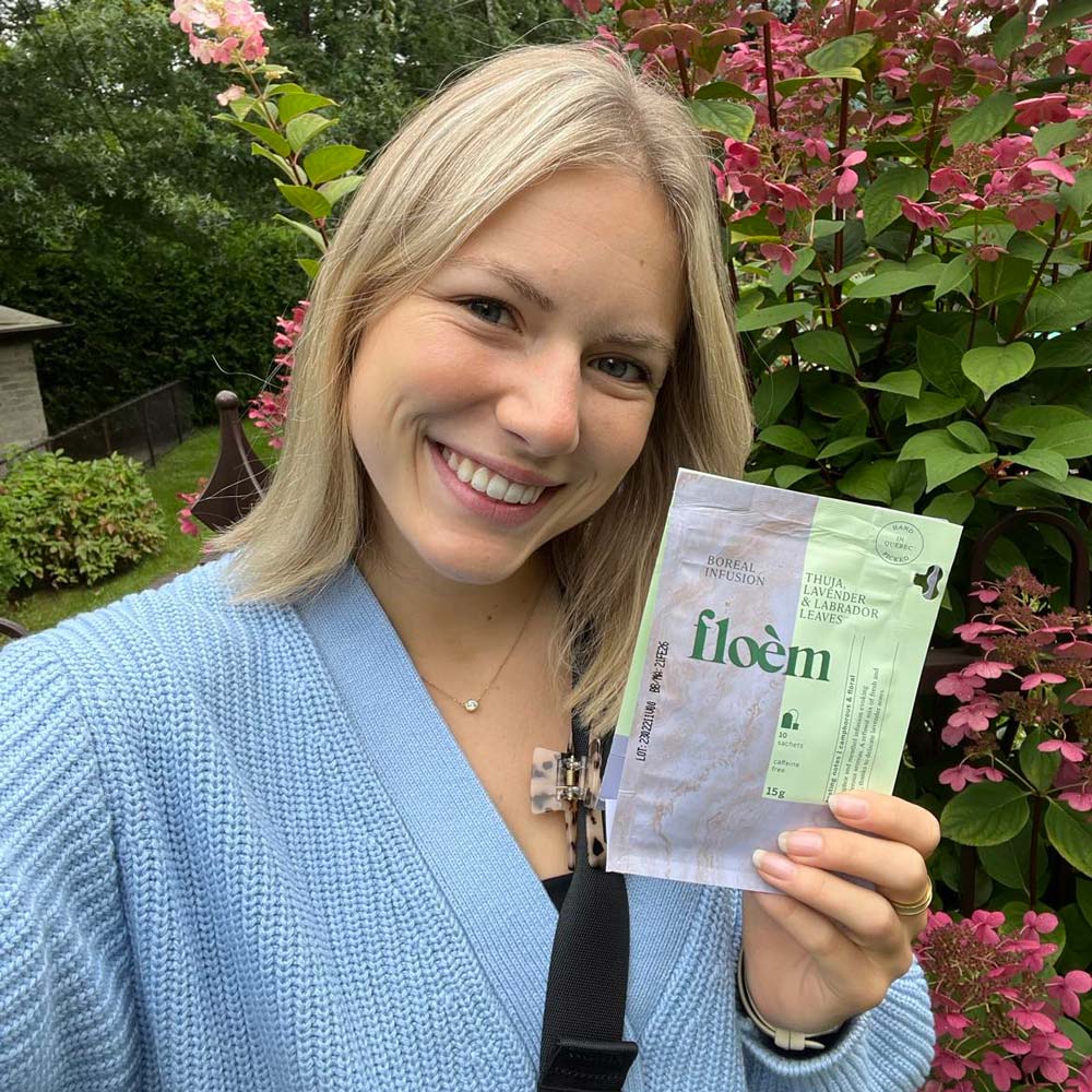 Cliente de Floèm souriante tenant un produit dans la nature
