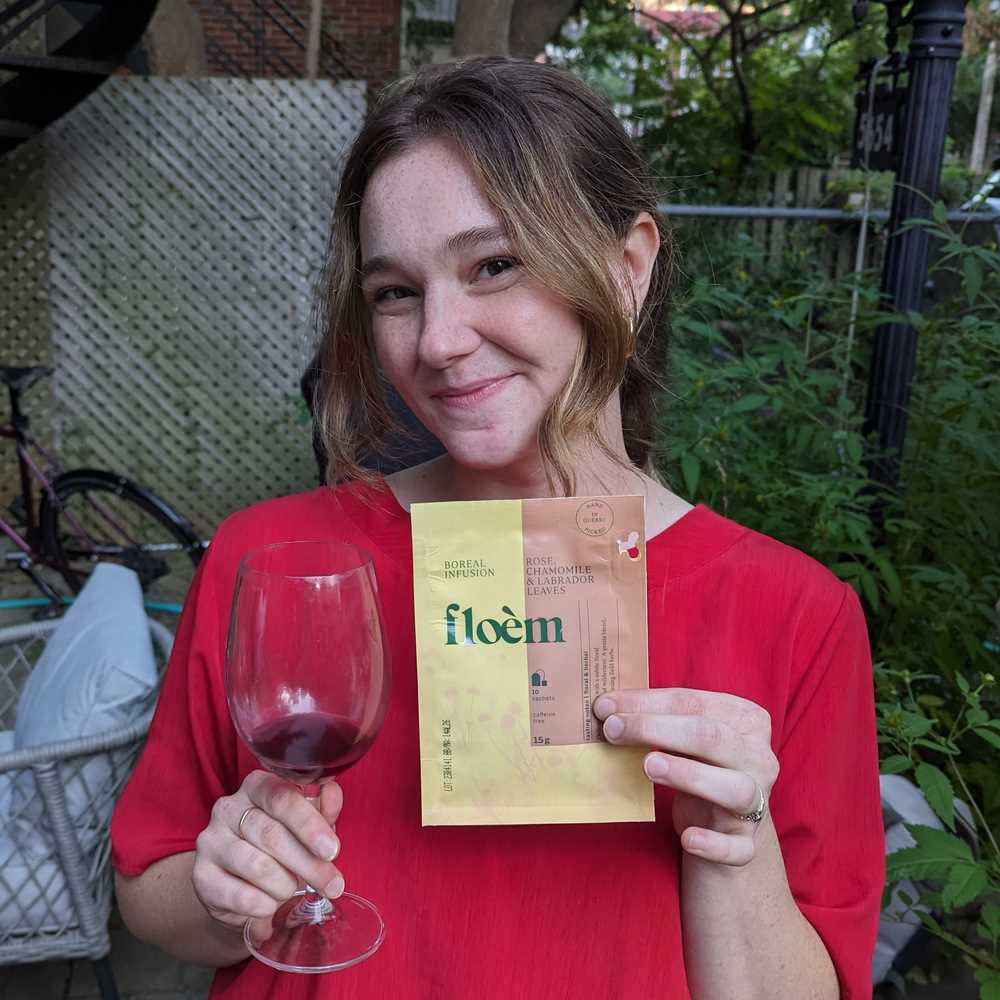 Cliente Floèm qui tient un sac de thé dans sa main et une coupe de vin